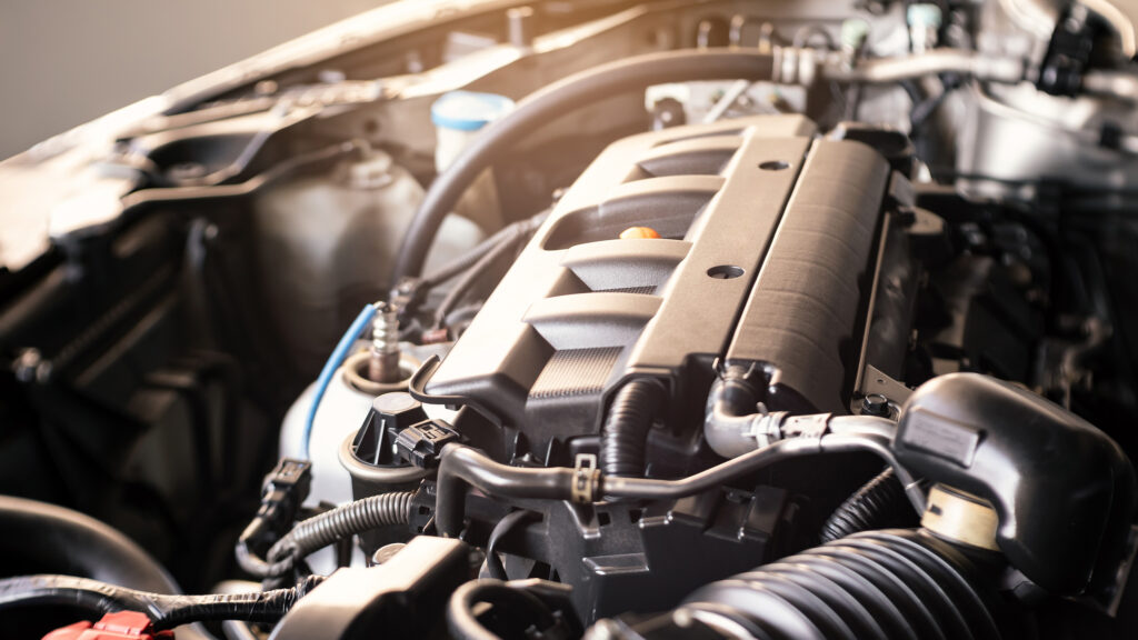 Close-up view of a car engine inside the engine bay, showing various components, wiring, and hoses.